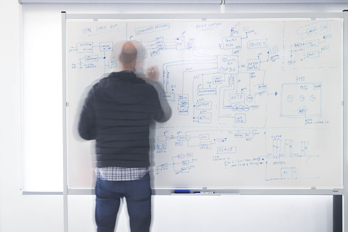 Engenheiro a desenhar um diagrama de sistema num quadro branco